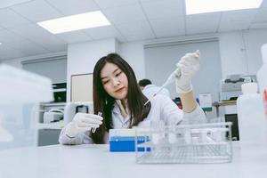 jovem cientista médico trabalhando em laboratório médico, jovem cientista usando pipeta automática para transferir amostra foto