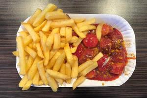 currywurst prato alemão de salsicha fatiada com molho de curry e batatas fritas foto