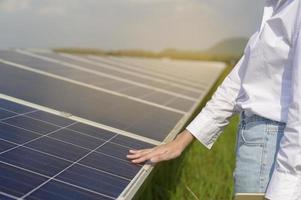 close-up do engenheiro de mão tocando com fazenda de células fotovoltaicas ou campo de painéis solares, energia ecológica e limpa. foto