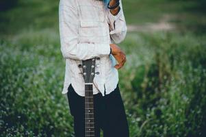 a mão do homem toca violão, toca violão no jardim sozinho, feliz e adora a música. foto