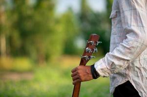 a mão do homem toca violão, toca violão no jardim sozinho, feliz e adora a música. foto