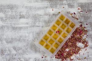 bebida feita de pétalas de rosa secas em forma de cubo de gelo antes de congelar no fundo branco foto