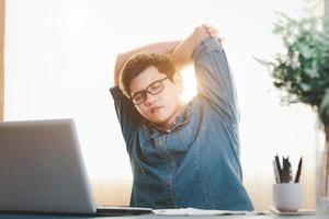 jovem empresário exercita esticando os músculos na mesa de trabalho, relaxe do trabalho duro. foto