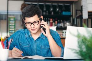 jovens asiáticos atendem o telefone felizes após um novo pedido do cliente, empresário que trabalha em embalagem de escritório em casa em segundo plano, comércio eletrônico de compras on-line ou conceito de trabalho freelance. foto