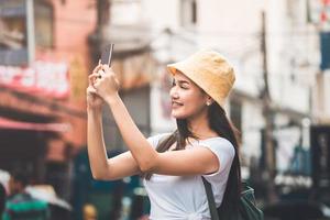 jovem mulher asiática viajando em bangkok. usando smartphone tirar foto. foto