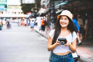 mulher feliz jovem viajante asiático segurando a câmera instantânea. foto