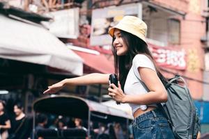 jovem mulher asiática segura câmera de filme instantâneo e chama táxi em bangkok, tailândia. foto