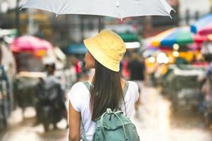 mulher viajante asiática sozinha com guarda-chuva entre chuva foto