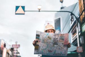 mulher asiática pesquisando com mapa em chinatown foto