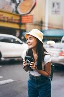 mulher jovem viajante asiática com câmera instantânea em bangkok, tailândia foto