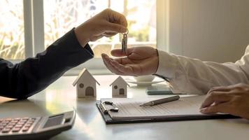 o agente imobiliário fornece as chaves da casa ao cliente após a assinatura do contrato imobiliário com um formulário de pedido de hipoteca aprovado. conceito de empréstimo hipotecário residencial e seguro residencial
