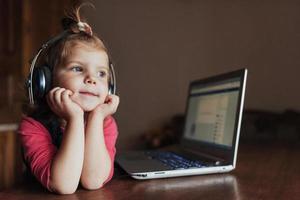 menina com fones de ouvido ouvindo música, usando laptop foto