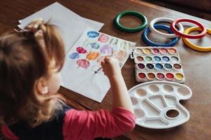 menina bonitinha desenha um círculo de tintas coloridas foto