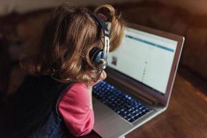 criança linda feliz em fones de ouvido, ouvindo música. foto