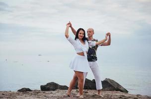 lindo casal inflamatório dançando na praia foto