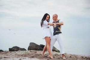 lindo casal inflamatório dançando na praia foto