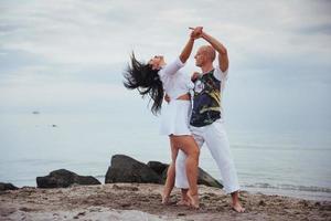 casal apaixonado dançando na praia do mar no verão foto