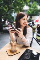 relaxe a mulher asiática no café usando telefone inteligente para mídias sociais. foto