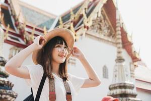 garota de mochila de influência asiática jovem viajando no templo bangkok. foto