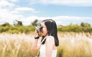 estilo de vida hipster de mulher asiática adulta jovem com câmera de filme vintage ao ar livre foto