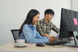 jovens programadores de parceiros asiáticos trabalhando em equipe ao fazer novos códigos de computador no computador desktop no escritório. foto