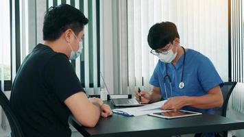os médicos estão explicando o tratamento da doença de um paciente usando uma máscara durante a epidemia. foto