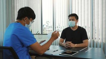 os médicos estão explicando o tratamento da doença de um paciente usando uma máscara durante a epidemia. foto