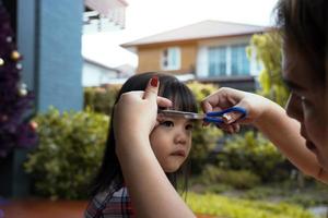 mãe estava cortando o cabelo para a filha em casa. foto