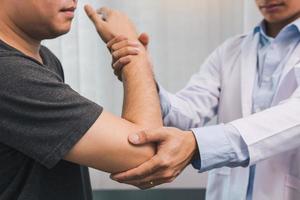 fisioterapeutas asiáticos verificam os cotovelos de pacientes submetidos à reabilitação ortopédica. foto