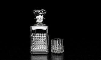 a garrafa e o copo têm um padrão elegante para conhaque ou uísque. a garrafa de vidro tem uma rolha em forma de diamante. a garrafa e o copo são cristalizados com fundo preto e foto