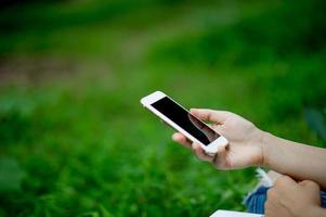 menina jogando telefone na mão para comunicação on-line e contato veste camisa vermelha e fundo verde e há um espaço de cópia. foto