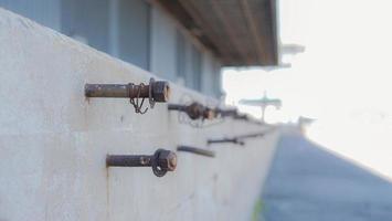 parafuso e parafuso são embutidos na parede de cimento. porca enferrujada embutida no suporte de cimento no armazém foto