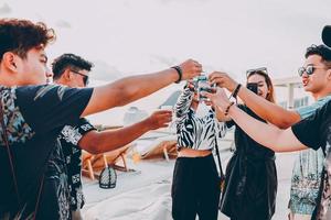 amigos asiáticos torcendo com coquetéis tropicais azuis nas férias de verão foto