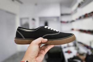 mão segurando sapatos de homem com fundo desfocado de loja de moda foto