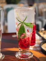 um copo de refrigerante italiano vermelho frio com folha de maconha ou cannabis.