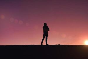 silhueta de homem trekking na montanha com um belo pôr do sol foto