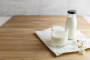 garrafa de leite e copo de leite na mesa de madeira foto