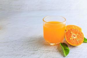 suco de laranja espremido na hora em um copo e frutas cítricas frescas em um fundo branco.