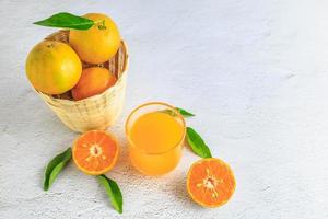 suco de laranja fresco com frutas laranja na cesta foto