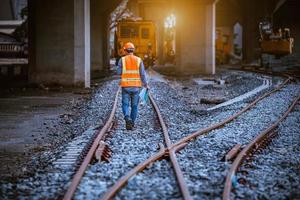 engenheiro ferroviário sob verificação do processo de construção, teste de trem e verificação do trabalho ferroviário na estação ferroviária com comunicação de rádio .engineer vestindo uniforme de segurança e capacete de segurança no trabalho. foto