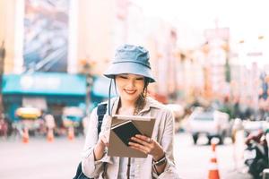 jovem adulto mulher asiática viajante solo viajando com ensino moderno usando tablet. foto
