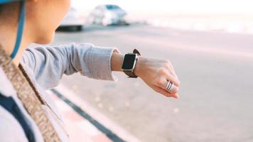 close-up mão mulher pessoas usam relógio inteligente verificando informações de tempo e saúde ao ar livre. foto