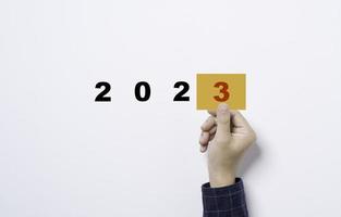 mão segurando papel amarelo com o número três para preparação do novo ano comercial de 2022 a 2023 conceito. foto