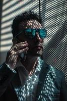 empresário respeitável em óculos de sol falando no smartphone foto