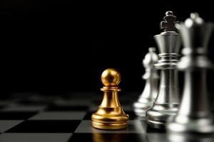 peão de xadrez dourado na frente de outro xadrez, o conceito de líder deve ter coragem e desafio na competição, liderança e visão de negócios para uma vitória em jogos de negócios foto