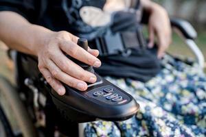 paciente mulher asiática em cadeira de rodas elétrica com joystick e controle remoto na enfermaria do hospital de enfermagem, conceito médico forte e saudável foto