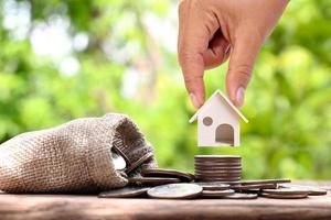 empresário segurando a casa modelo em uma pilha de moedas de conceito de investimento hipoteca e taxa de juros de construção de casa foto