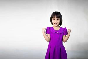 retrato de menina bonita asiática de uma menina alegre em t-shirt cinza, olhando para a câmera e piscando fundo isolado. garota caucasiana emocional. criança Feliz foto