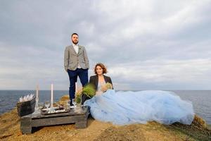 sessão de fotos de casamento de um casal à beira-mar. vestido de noiva azul na noiva.