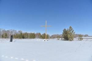 cruz cristã no campo no inverno na floresta foto
